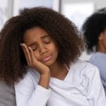 Sad African American teenage daughter sit on couch feel upset after fight with mom, mother and child avoid talking having understanding problems, teen girl disappointed with family relationships